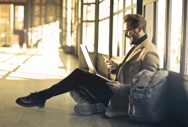 Remote compliance - a businessman sat on the floor working on his laptop.