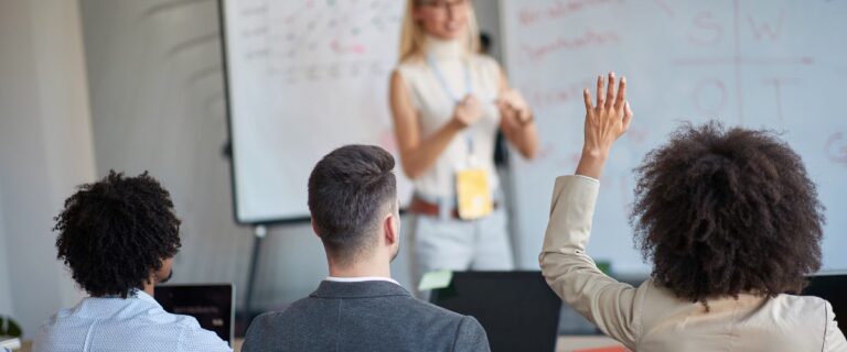 Continuous compliance training - a lady standing in front of a group of people - educating and training them in continuous compliance.