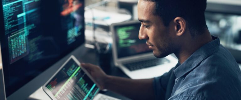 Data visualization - A developer checking data on a tablet, surrounded by monitors.