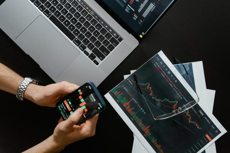 Fintech solutions - somebody checking financial graphs on a mobile and laptop.