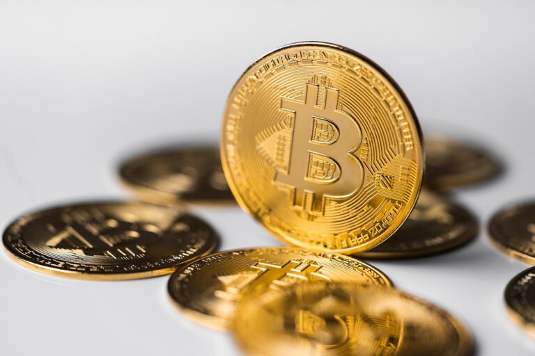 A few Bitcoins laying on a table and one standing upright.