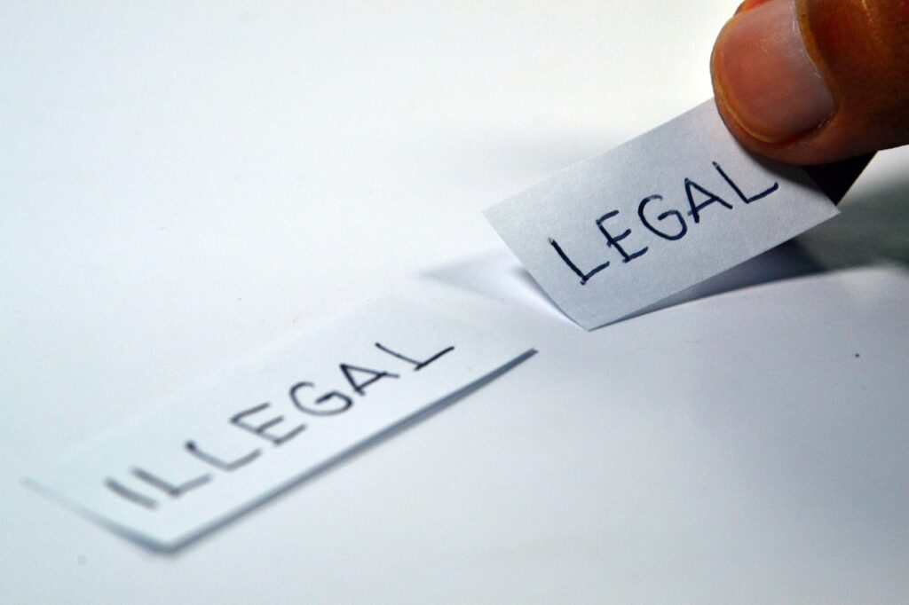 Two pieces of paper being joined together, one says illegal and the other one says legal.