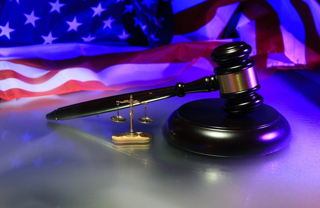 Department of Justice in America, depicted by the scales of justice, a judge's gavel and the flag of America.