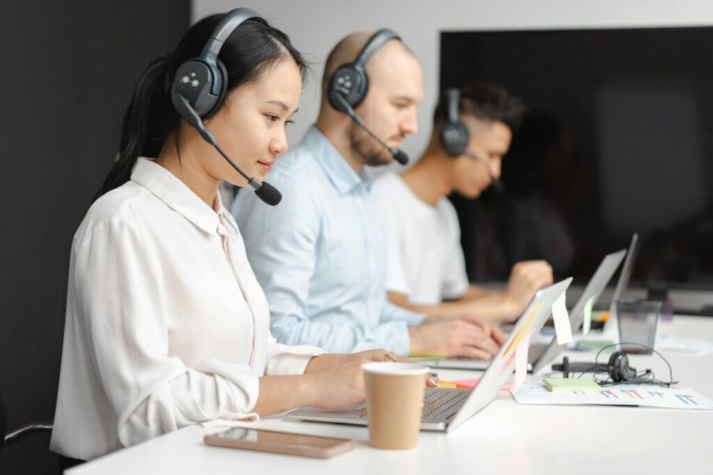 A woman and two men working in a call centre for customer service.